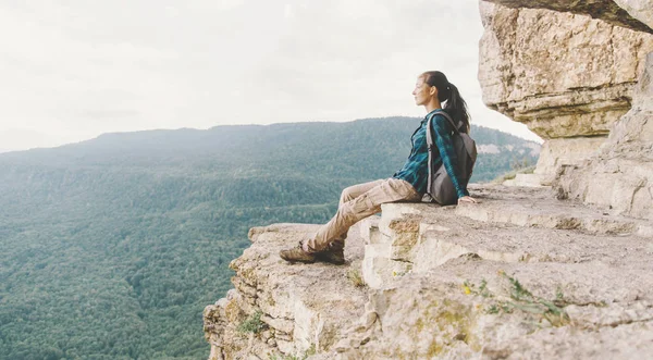 Backpacker junge Frau ruht sich auf Klippe aus. — Stockfoto