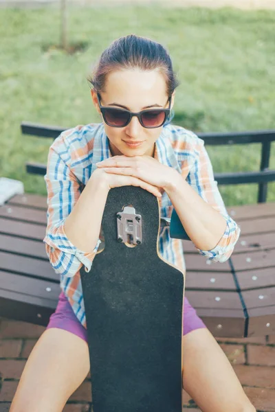Chica con longboard sentado en el banco . —  Fotos de Stock