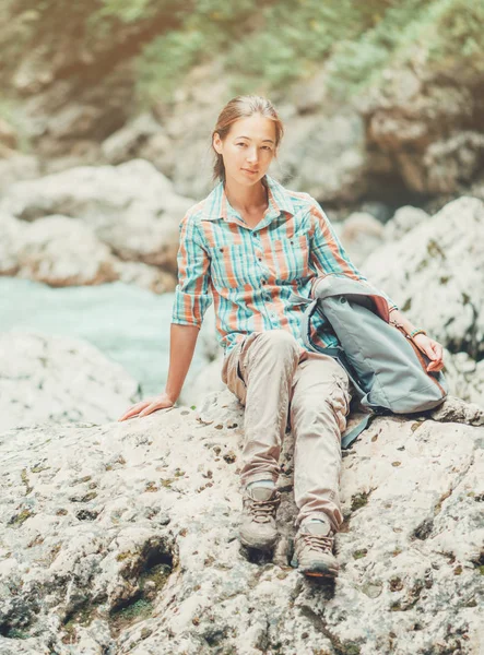 Explorer girl sitting on rocky stone. — Stock Photo, Image