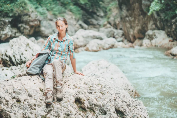 Backpacker-Frau sitzt am Flussufer. — Stockfoto