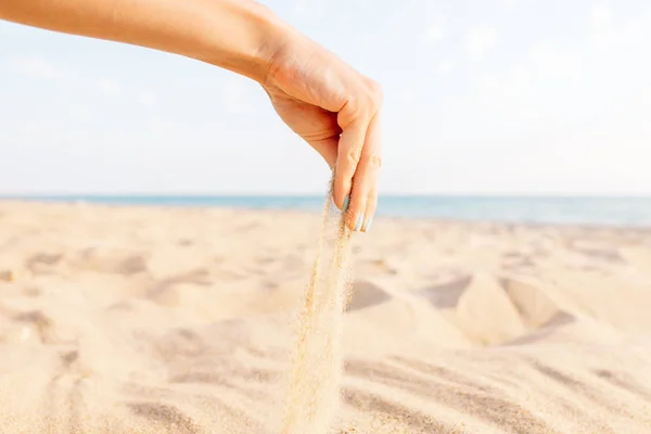 Female hand pours sand on beach. — Stock Photo, Image