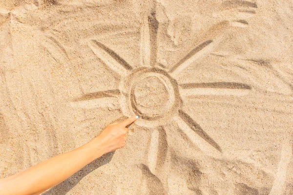 Female hand draws sun on the sand. — Stock Photo, Image