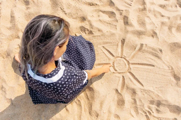 Girl draws on the sand with her finger. — Stock Photo, Image