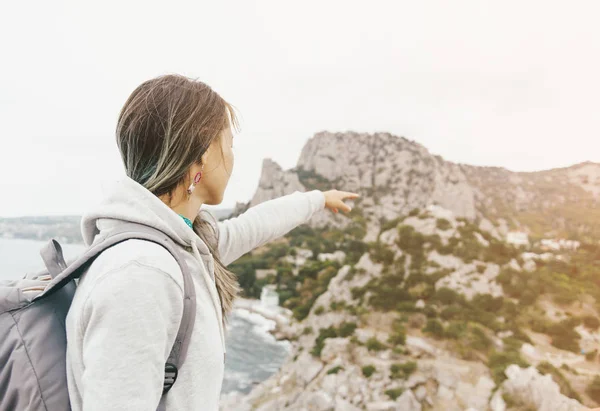 Backpacker woman pointing at cliff on coastline. — Stock Photo, Image