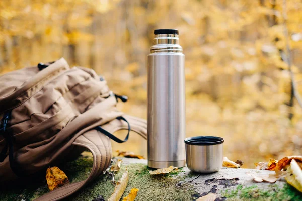 Plecak i termos butelka w lesie jesienią. — Zdjęcie stockowe