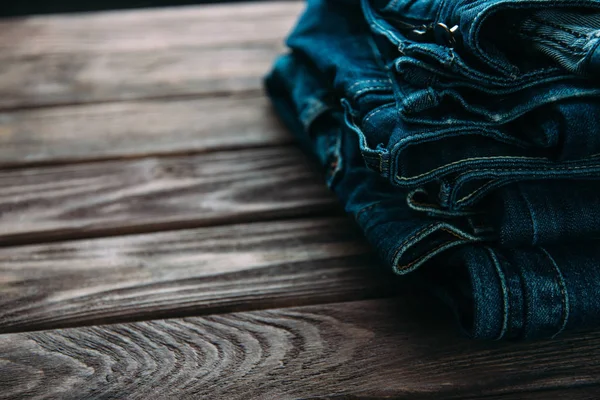 Stos dżinsy spodnie na drewnianym stole. — Zdjęcie stockowe