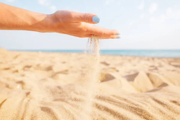 Sand som rinner genom hand på stranden. — Stockfoto