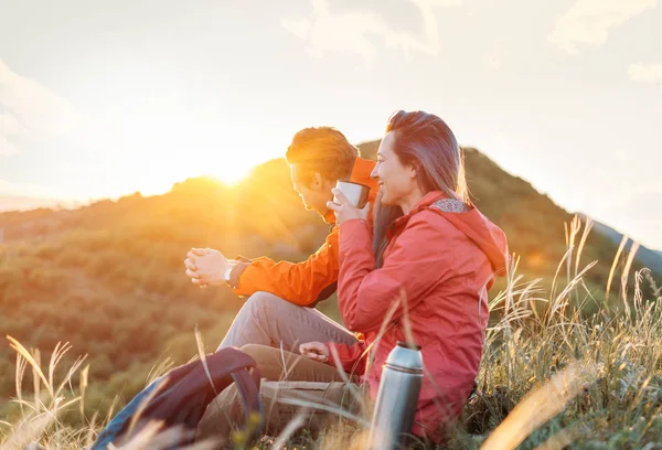 Gelukkig reiziger paar rust in de bergen bij zonsondergang. — Stockfoto