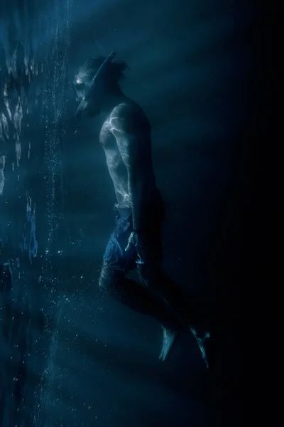 Volný muž potápěč, plavání pod vodou blízko povrchu. — Stock fotografie