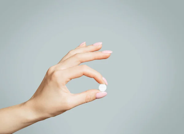 Mano femenina sosteniendo una píldora blanca redonda o vitamina . —  Fotos de Stock