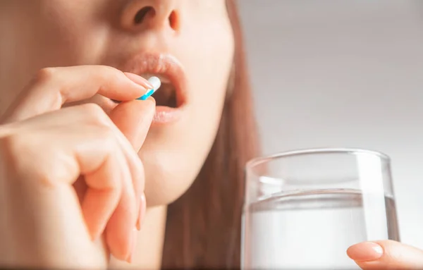 Mulher segurando copo de água e tomando uma pílula médica ou vitaminas — Fotografia de Stock