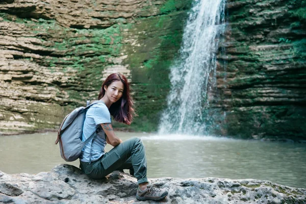 Backpacker-Mädchen ruht sich vor Wasserfall und Lagune aus — Stockfoto