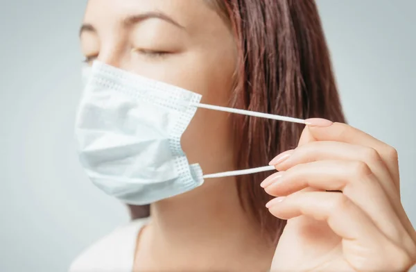 Woman puts on a medical protective facial mask against air infec — Stock Photo, Image