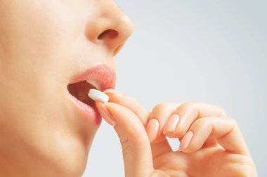 Beyaz yuvarlak hap ya da vitamin alan bir kadın.