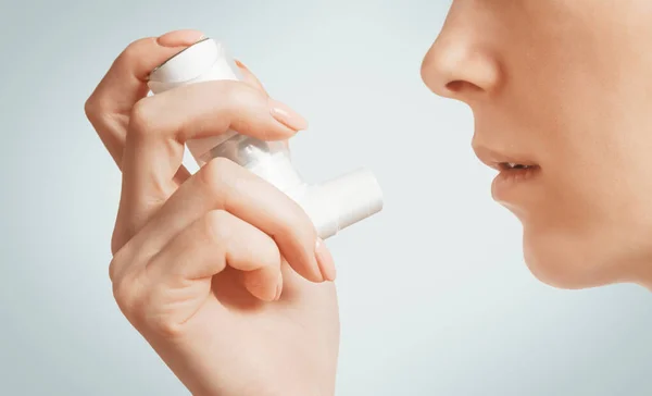 Mujer sosteniendo inhalador médico de asma cerca de su cara . —  Fotos de Stock