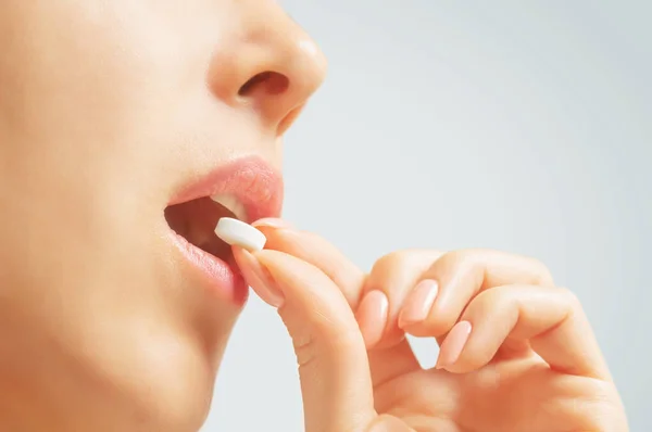 Mulher tomando uma pílula redonda branca ou vitamina . — Fotografia de Stock