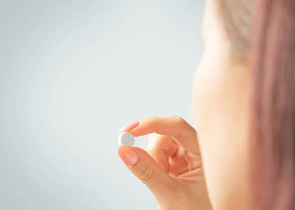 Mulher segurando um comprimido de medicação ou vitamina . — Fotografia de Stock