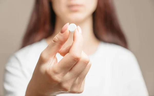 Woman holding a white round pill or vitamin. — Stock Photo, Image