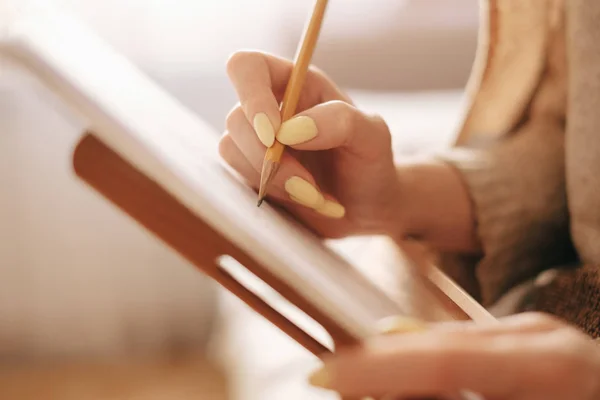 Close-up of female hand drawing on paper easel with pencil. — Stock Photo, Image