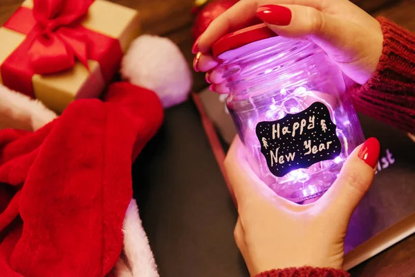 Woman opening a glowing jar with inscription Happy New Year. — Stock Photo, Image