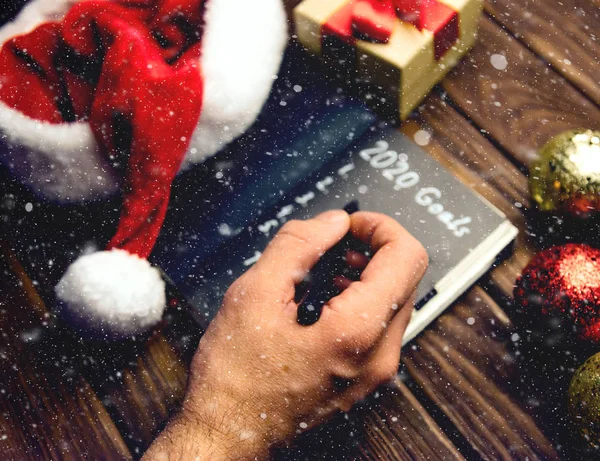 Uomo scrivere obiettivi 2020 a Capodanno con effetto neve . — Foto Stock