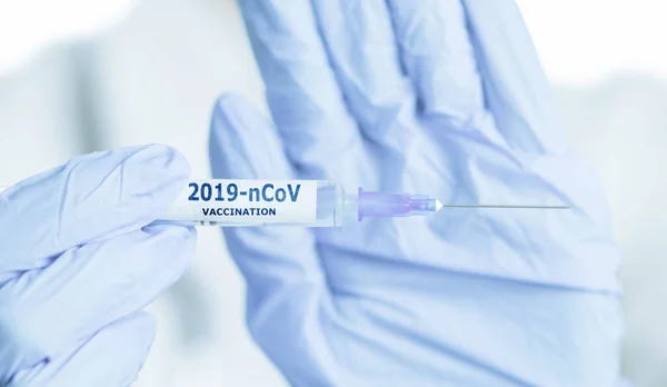 Mãos de médico em luvas mostrando seringa com vacinação 2019-nCo — Fotografia de Stock