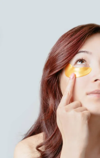 健康的な新鮮な肌のための眼パッチの下に黄金の美しい若い女性のハーフ顔の肖像画 — ストック写真