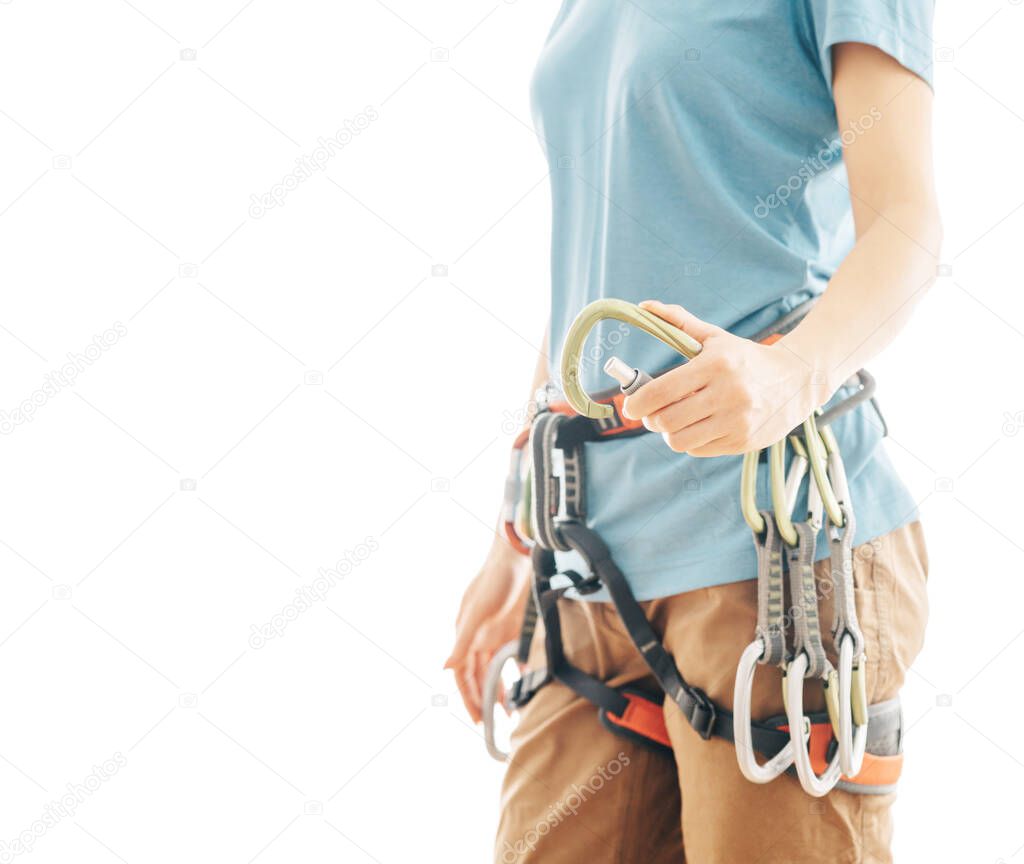 Unrecognizable woman climber in safety harness holding snap hook carabiner on a white background with copy-space.