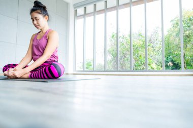 Asyalı kadınlar yoga antrenmanı yapıyor. Pembe kıyafetler giyiyorlar.