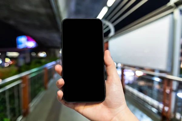 Uso femenino sosteniendo la mano del teléfono inteligente con pantalla negra vacía borrosa — Foto de Stock