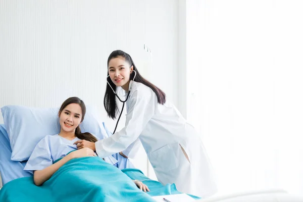Asiatico giovane paziente femminile sul letto mentre medico mani di controllo — Foto Stock