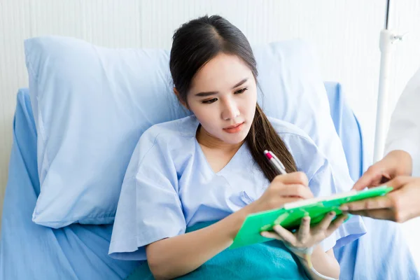 Asian young female patient Signature for consent form on bed to