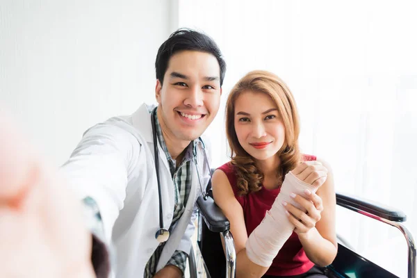 Selfie de homem sorridente médico com um paciente do sexo feminino desgaste braço spli — Fotografia de Stock