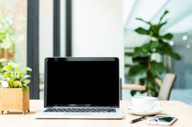 Boş ekranlı dizüstü bilgisayarın modeli ve kahve fincanı.