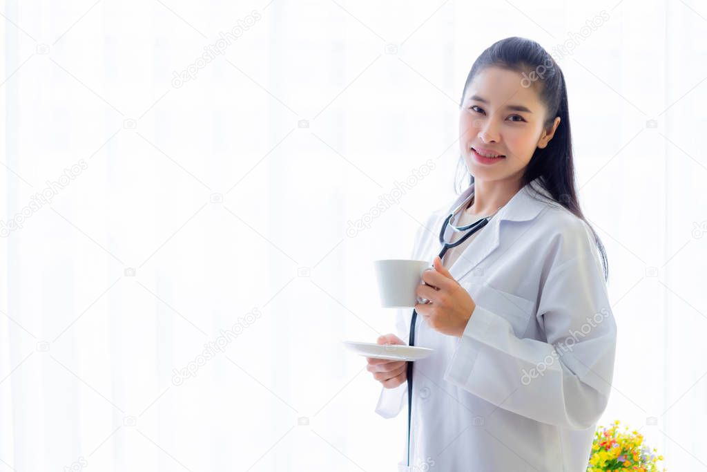 Portrait of asian young female doctor eating coffee from a cup a