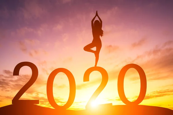 Mutlu yıllar 2020, Siluet kadın erkenden yoga yapıyor.