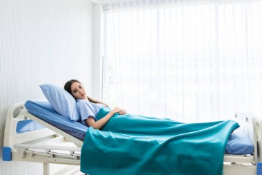Yatakta kaygılı yüzü olan Asyalı genç bir hasta.