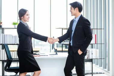 Asyalı iş kadını ve işadamı el sıkışıyor.