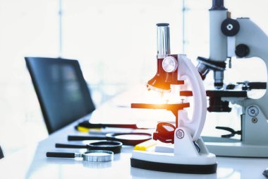 Laboratuvarda cam parçalı mikroskop ve test tüpleri.