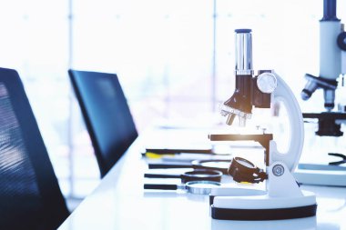 Laboratuvarda cam parçalı mikroskop ve test tüpleri.