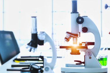 Laboratuvarda cam parçalı mikroskop ve test tüpleri.