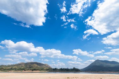 Mae Khong nehrinin kuru kum zemini, mavi dağ manzaralı.