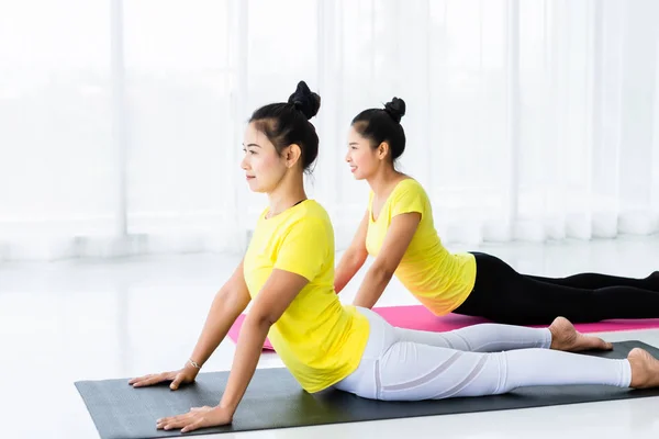 Dos mujeres asiáticas jóvenes practican yoga en vestido amarillo o —  Fotos de Stock