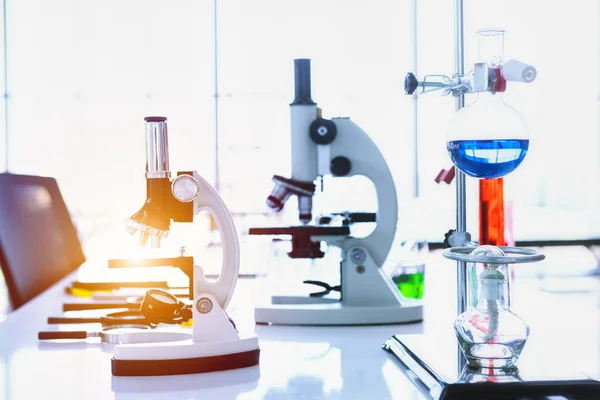 Microscopio y tubos de ensayo con cristalería de laboratorio en respaldo de laboratorio — Foto de Stock