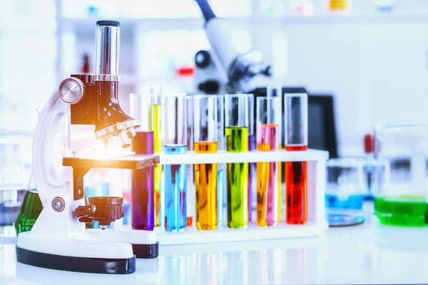 Microscopio y tubos de ensayo coloridos con cristalería de laboratorio en laboratorio — Foto de Stock