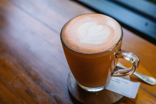 Hot Thai tea latte with latte art milk foam in glass mug with wo — ストック写真