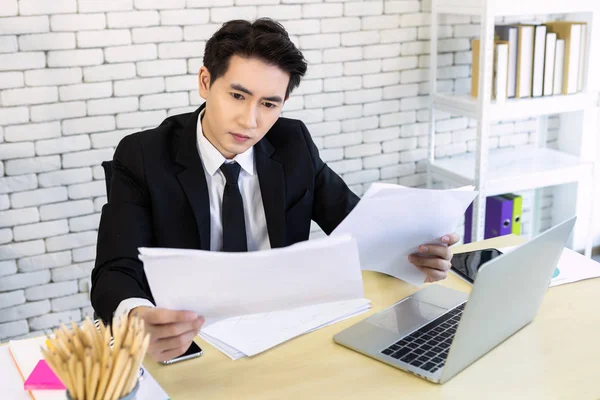 Asiatisk ung affärsman har betonat se ett dokument buske — Stockfoto