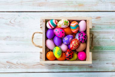Paskalya bayramı konsepti, beyaz pastel renkli ahşap kaplama sepetli renkli Paskalya yumurtaları..