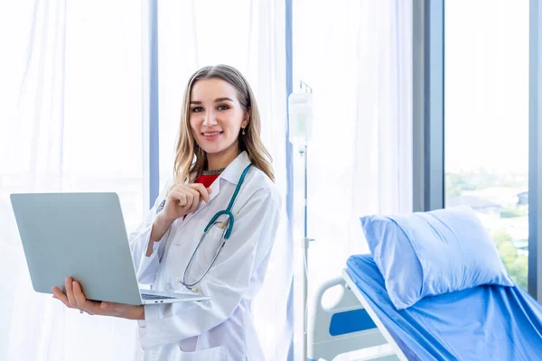 청진기를 가지고 의사는 노트북 컴퓨터를 가지고 일하며 뒷배경에 서류를 — 스톡 사진