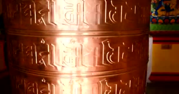 Bhuddhist prayer wheel golden inscribed with a sanskrit prayer and creamy bokeh . — 图库视频影像